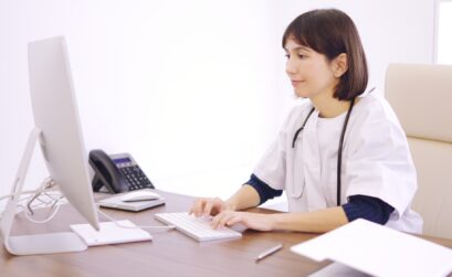Doctor using computer sitting on a desk in a clinic