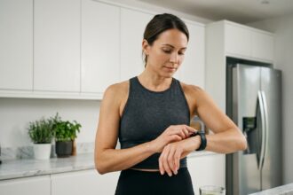 Femme consultant une montre connectée dans une cuisine moderne pour suivre ses données de santé et ses objectifs minceur au quotidien